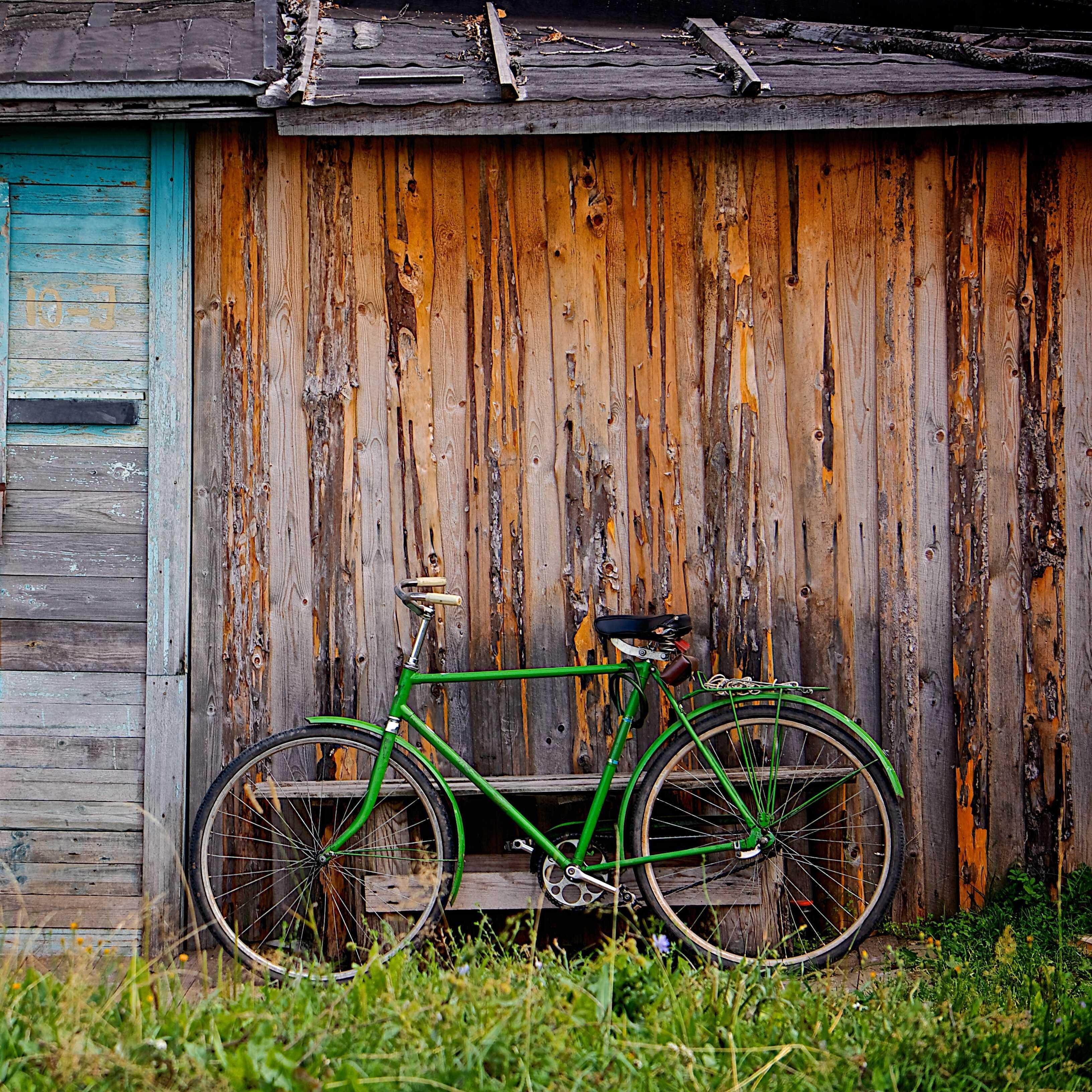 Ein grünes Fahrrad lehnt an einer alten Holzhütte.