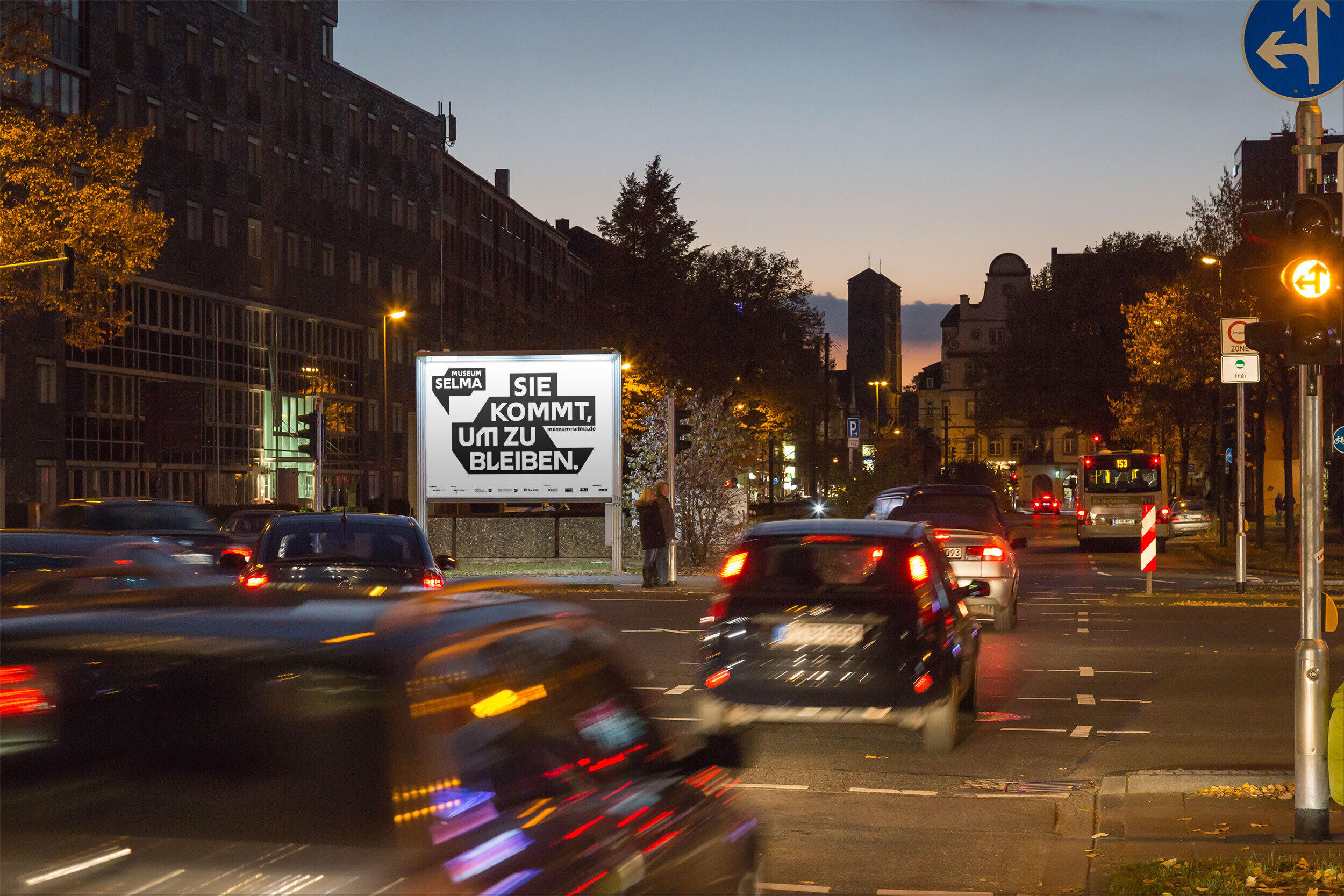 Ein beleuchtetes Werbeplakat für das Museum Selma, an einer Hauptstraße in Köln.